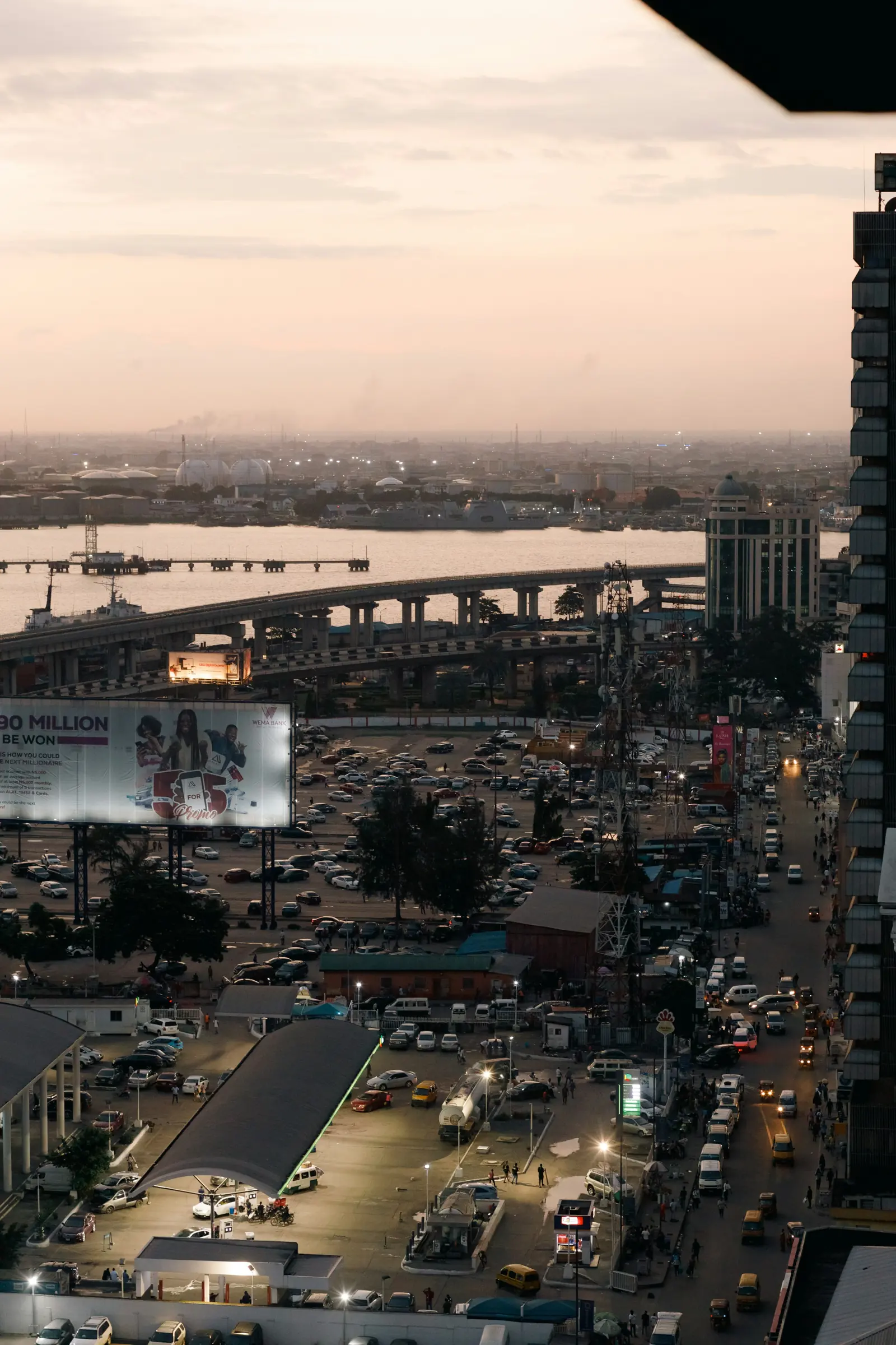 Aerial view of busy Lagos traffic at dusk with a bridge behind